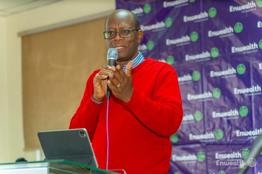 A speaker addressing an audience in front of an Enwealth backdrop.